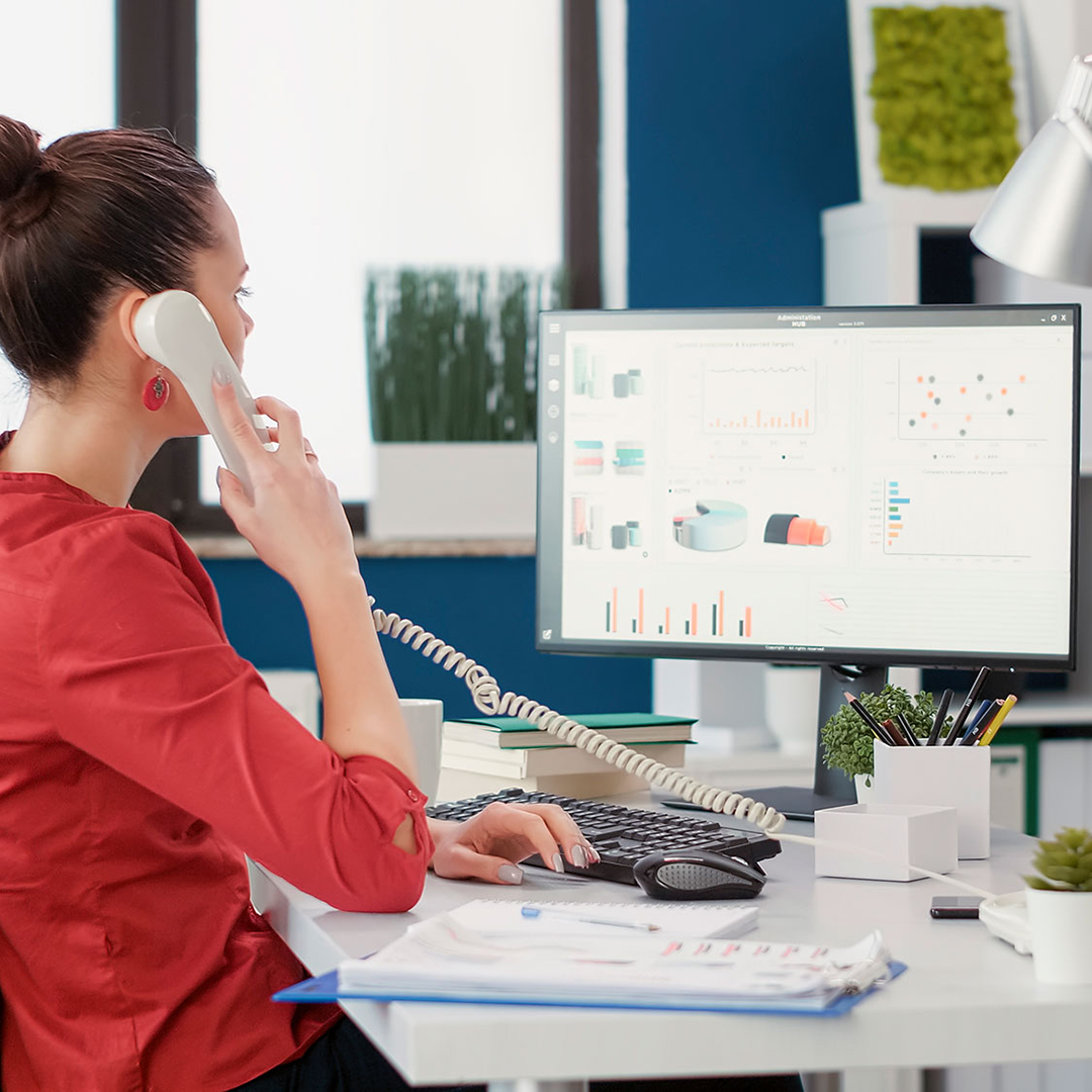 Office secretary using landline phone to talk about work
